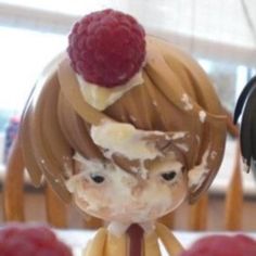 two figurines sitting on top of a table with raspberries in front of them