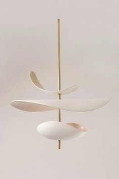 three white and gold objects hanging from a metal rod in a room with light colored walls