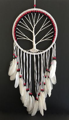 a white dream catcher with feathers hanging from it's side and a tree on top