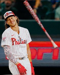 a baseball player holding a bat in his right hand and wearing gloves on the other side