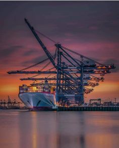 a large cargo ship in the water at sunset with cranes on it's side