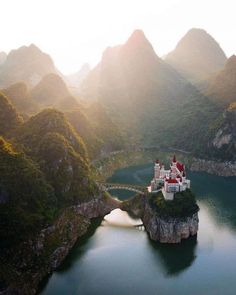 an aerial view of a castle in the middle of a lake surrounded by mountains and trees