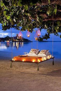 a bed with lights hanging from it's sides in front of a body of water