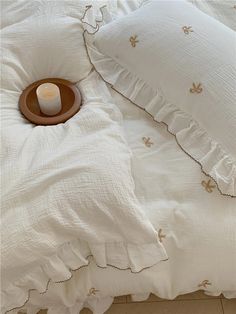 a bed with white linens and a brown plate on top of the pillow cover