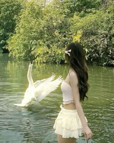 a woman is standing in the water with two swans