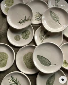 many plates with leaf designs on them are arranged in a pile and one is empty