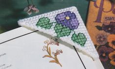 a piece of crocheted paper sitting on top of a table next to flowers