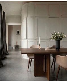 a dining room table with chairs and a vase filled with flowers