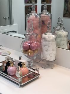 the bathroom counter is filled with bath products and candies in glass containers on it