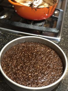 an orange bowl filled with ice cream next to a metal pan on top of a stove