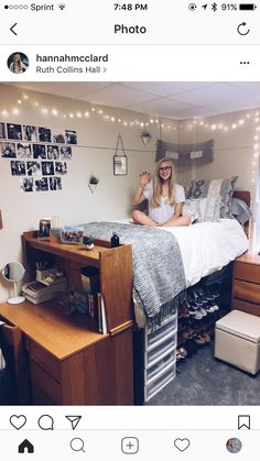 a woman sitting on top of a bed next to a wooden desk and drawers in a room