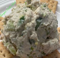 a white plate topped with crackers and a bowl filled with food on top of it