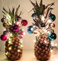 two pineapples decorated with christmas ornaments and lights on the sides, sitting next to each other