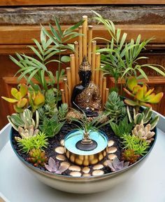 a bowl filled with plants and buddha statues