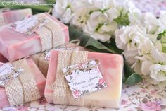 several soap bars with tags on them sitting next to white flowers and twine ribbons