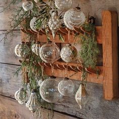 a wooden shelf with glass ornaments hanging from it's sides and greenery on the top