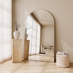 a mirror sitting on top of a wooden floor next to vases