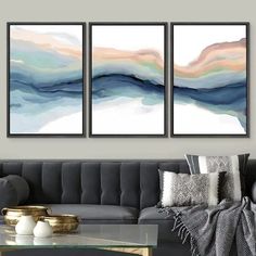 two paintings on the wall above a couch in a living room, one is blue and white