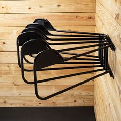 four black chairs hanging from the side of a wooden wall