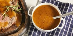 roast beef with gravy in a white bowl on a wooden tray next to a blue and white checkered napkin