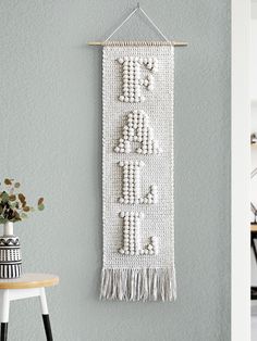 the wall hanging is decorated with beads and tassels, along with a potted plant