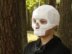 a woman wearing a paper skull mask in the woods