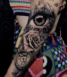 a woman's arm with an eye and rose tattoo on it