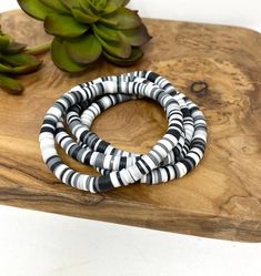 three bracelets sitting on top of a wooden board next to a succulent plant