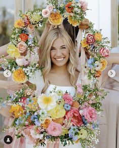 a woman standing in front of a wreath with flowers on it and holding her hair