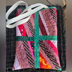 a colorful patchwork bag sitting on top of a basket next to a white ribbon