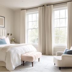 a white bed sitting next to two windows in a bedroom