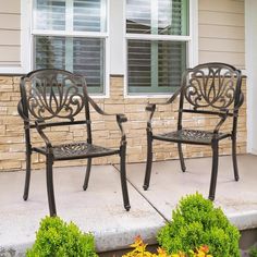 two metal chairs sitting on top of a cement patio next to a building with windows