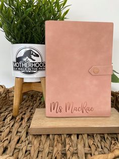 a pink notebook sitting on top of a wooden stand next to a potted plant