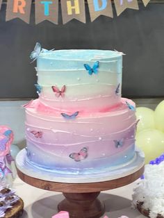 a multi layer cake sitting on top of a wooden table next to balloons and bunting