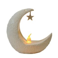 a white ceramic moon with a lit candle in the shape of a star and crescent