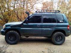 a blue suv parked on top of a dirt road