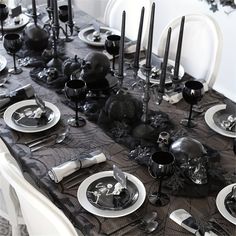 the table is set with black and white plates, silverware, and skull decorations