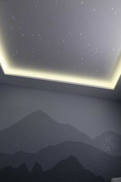 an empty room with mountains and stars painted on the wall, under a ceiling light