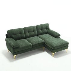 a green sectional couch sitting on top of a white floor next to a footstool