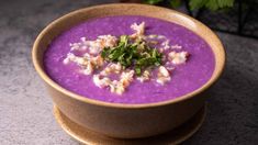 a bowl filled with purple soup and garnished with green leafy toppings