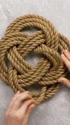 someone is tying a rope to a large knot on the floor with their hands and fingers