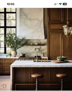 a kitchen with marble counter tops and wooden cabinets, along with two stools in front of the island