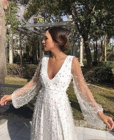 a woman in a white dress is standing outside