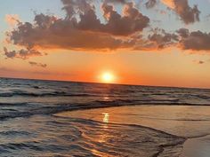 the sun is setting over the ocean with clouds in the sky and water on the beach