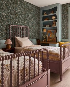 two twin beds in a bedroom with blue walls and floral wallpaper on the walls