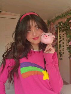 a girl in a pink sweater holding a pig toy