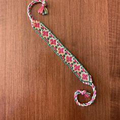 a colorful bracelet on top of a wooden table next to a keychain and lanyard