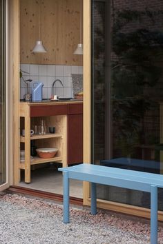 a blue bench sitting in the middle of a patio next to a kitchen and dining area