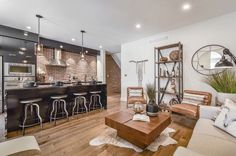 a living room filled with furniture next to a kitchen and dining room table in front of a brick wall