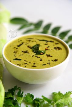 a white bowl filled with soup and garnished with parsley on the side